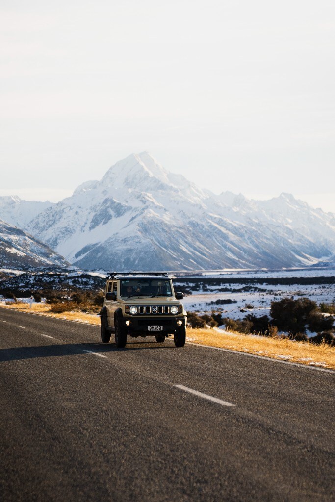 Suzuki Jimny heading into snow-covered alpine valley, South Island New Zealand