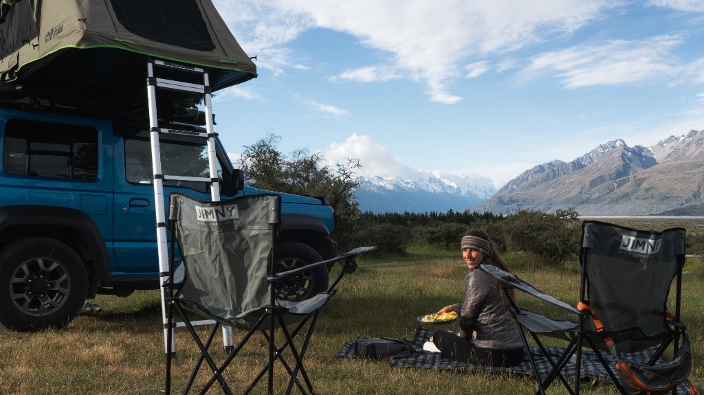 Suzuki Jimny by lake with snow-capped mountains, Queenstown region.